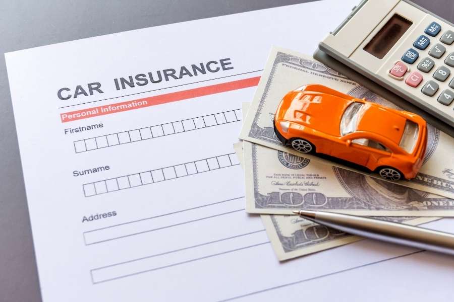 Formulaire de demande d'assurance auto, petite voiture orange et calculatrice pour gérer son budget assurance auto.