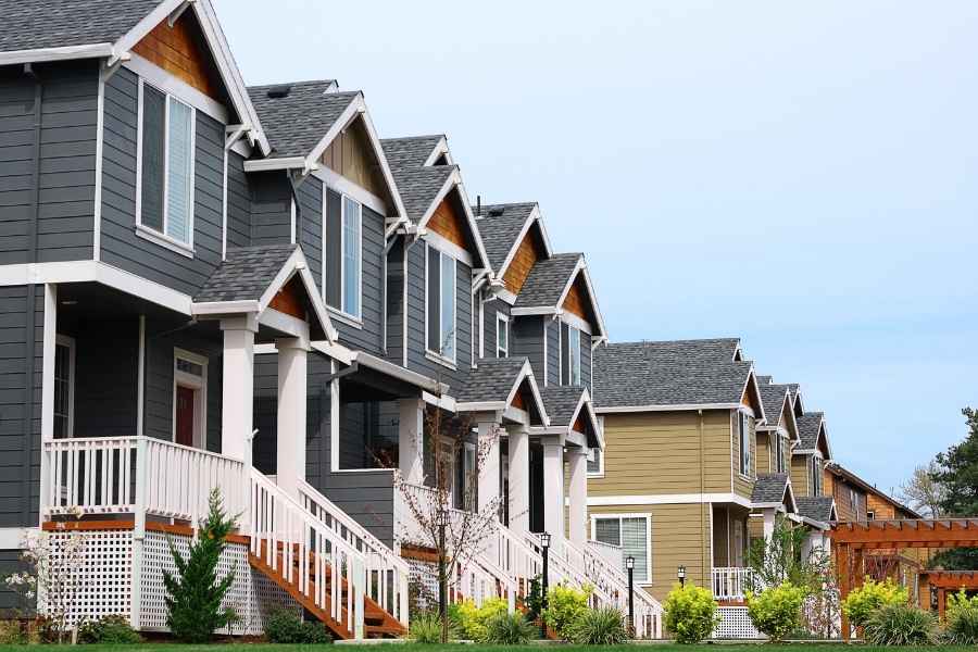 Une rangée de maisons mitoyennes modernes aux façades grises et aux balcons blancs, illustrant le choix entre une SCI ou nom propre pour gérer un patrimoine immobilier.